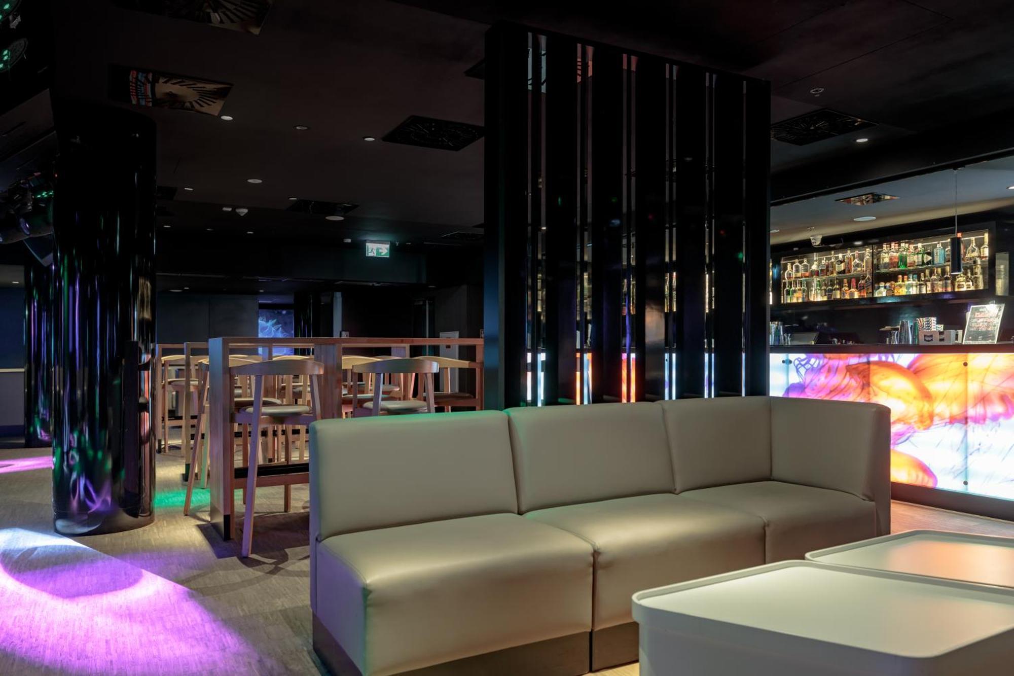 Radisson Blu Resort Swinoujscie Kültér fotó The photo shows the interior of a stylish lounge or bar. The space features a modern design with dark walls and a sleek atmosphere. There is a beige sectional sofa in the foreground, providing a casual seating area. In the background, a bar is visibl