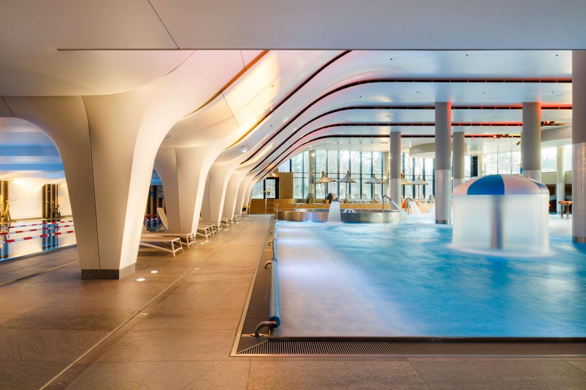 Radisson Blu Resort Swinoujscie Kültér fotó The photo shows an indoor swimming pool area with a modern architectural design. The space features large windows allowing natural light to enter, and the interior has smooth, flowing lines in the ceiling and columns. The pool has a light blue water 
